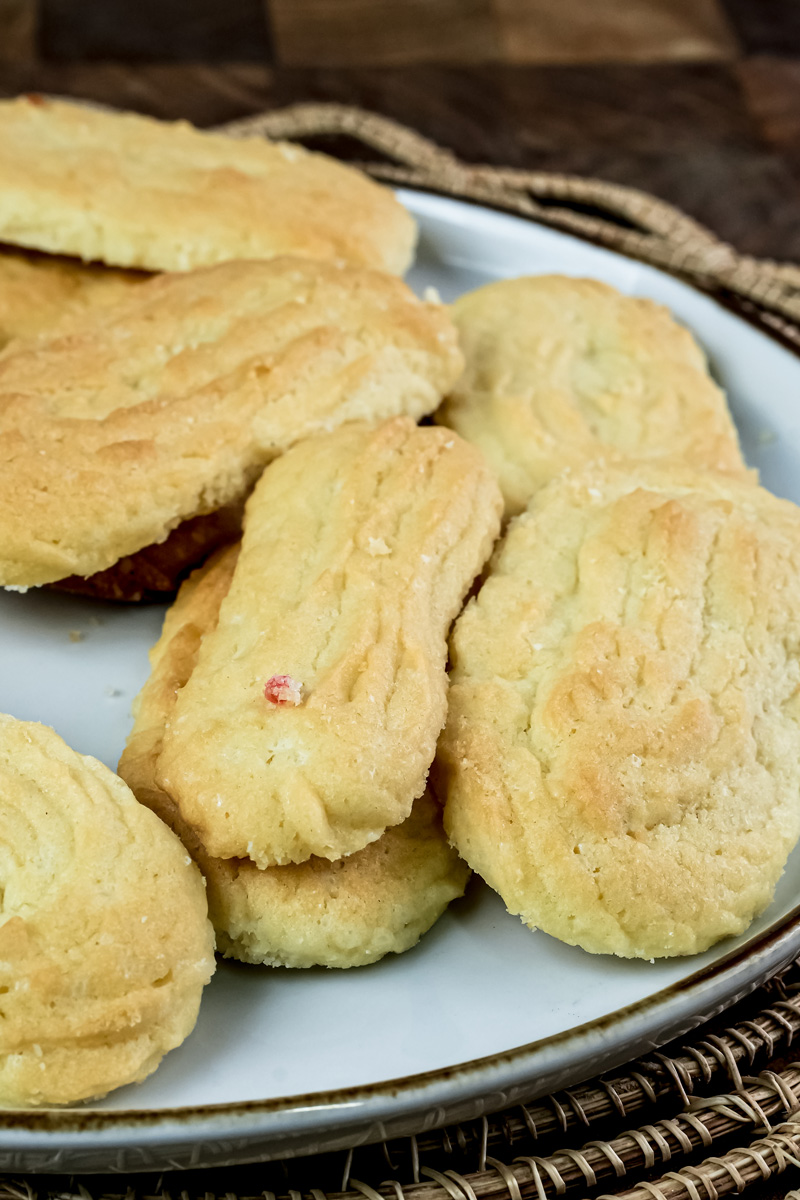 A close-up of a pile of freshly baked spritz cookies on a white plate