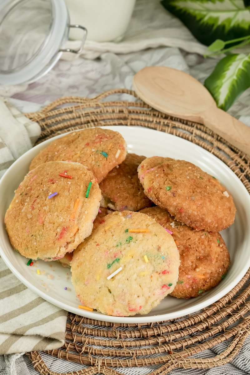A full plate of baked Funfetti cookies on a woven mat