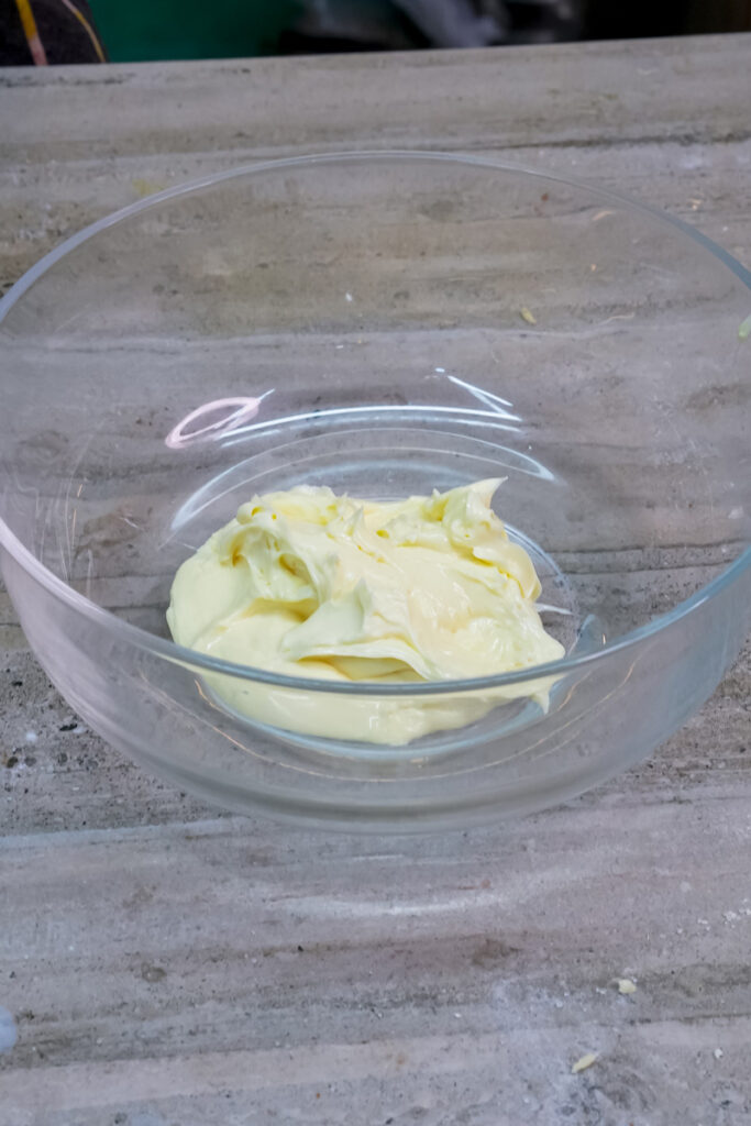 A clear glass bowl containing softened butter