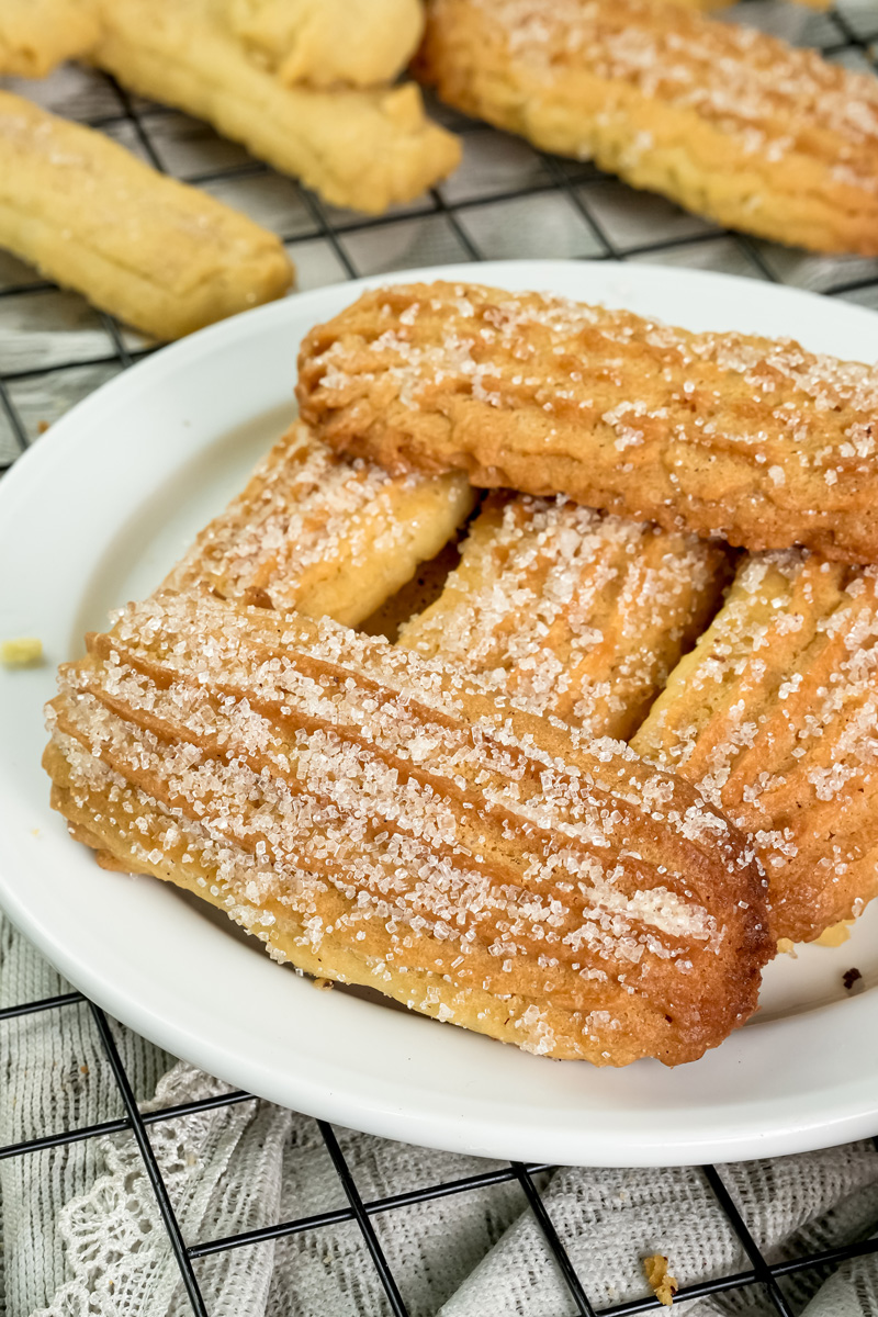 Close-up of golden brown churro cookies coated in cinnamon sugar on a white plate