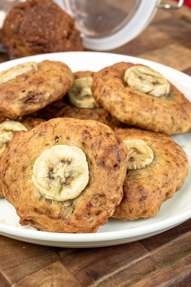 A close-up view of a pile of freshly baked banana cookies on a white plate