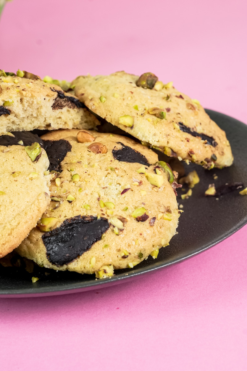 An angled view of a plate of delicious pistachio chocolate chunk cookies