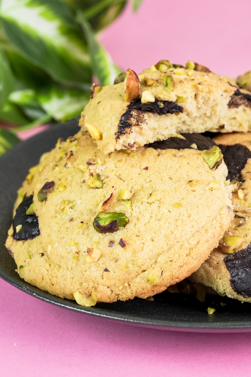 Close-up of a plate of fresh pistachio cookies, with a plant in the background