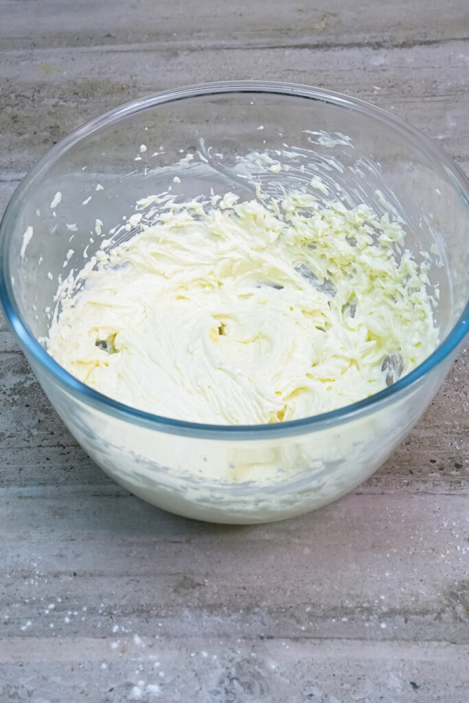 A close-up of the smooth, fluffy, and light-colored creamed butter, sugar, egg, and vanilla mixture in a glass bowl
