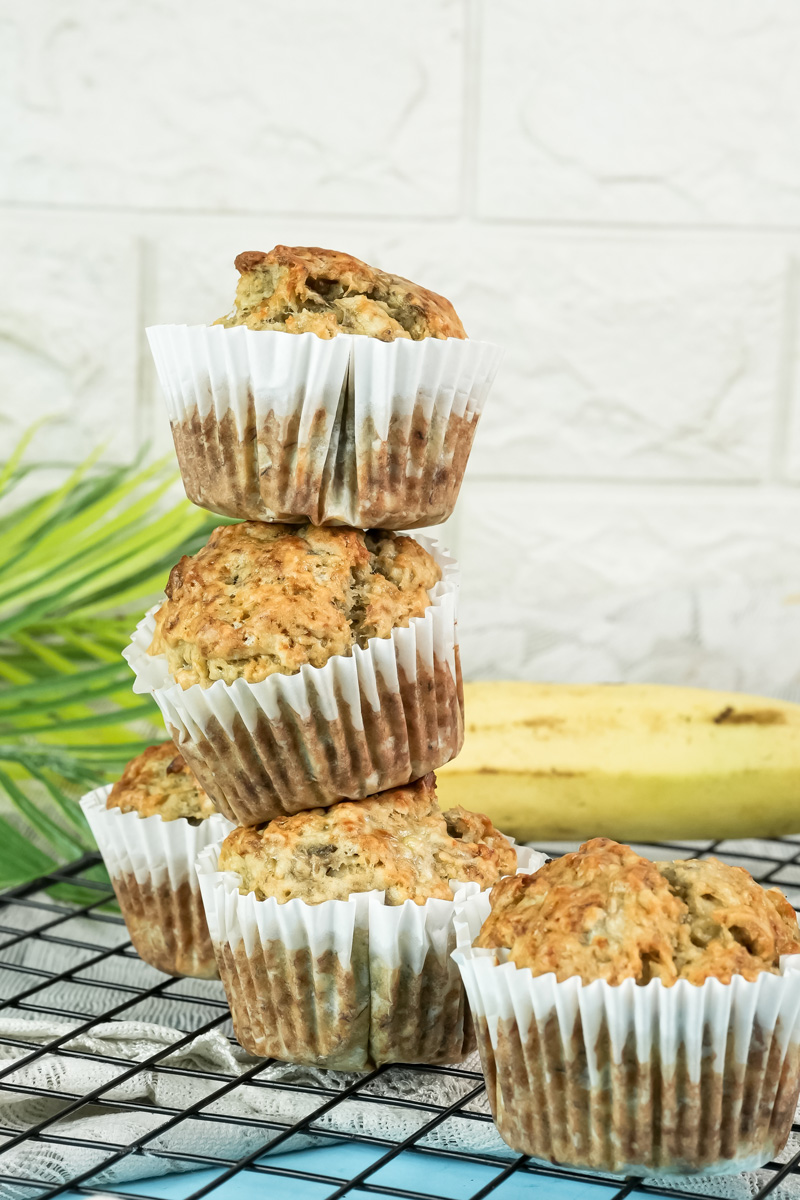 A stack of three homemade banana protein muffins, with others scattered around them