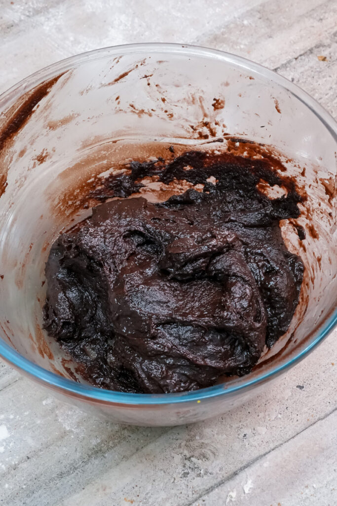 The fully mixed, thick chocolate crinkle cookie dough in a bowl.
