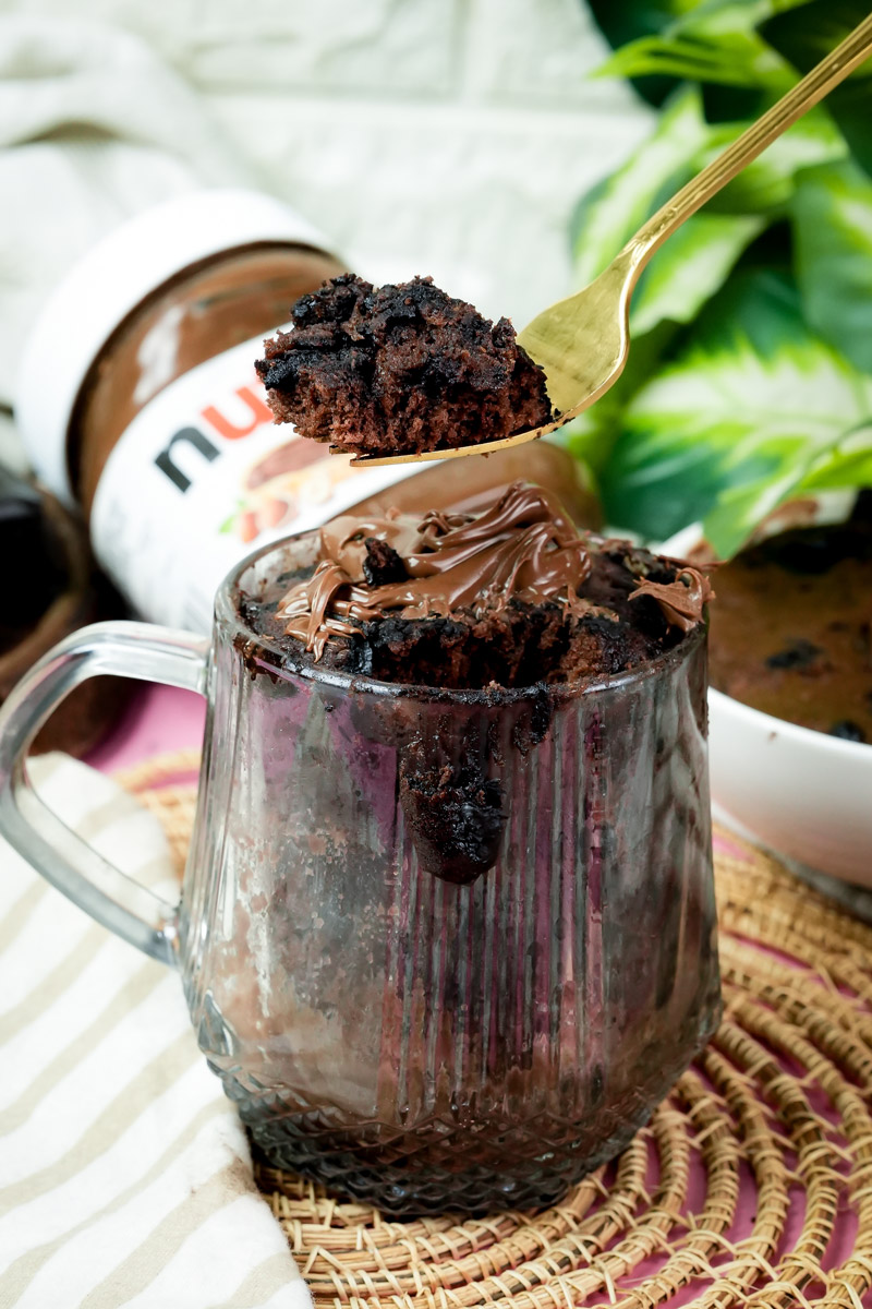 A bite of moist flourless chocolate mug cake on a gold spoon