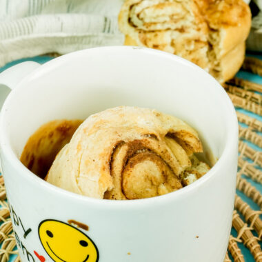 A warm cinnamon roll in a mug with a smiley face design