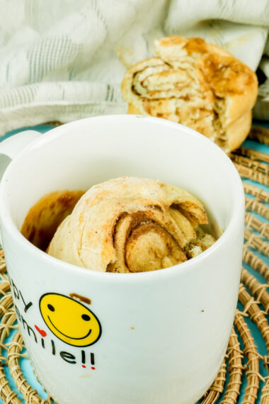 A warm cinnamon roll in a mug with a smiley face design