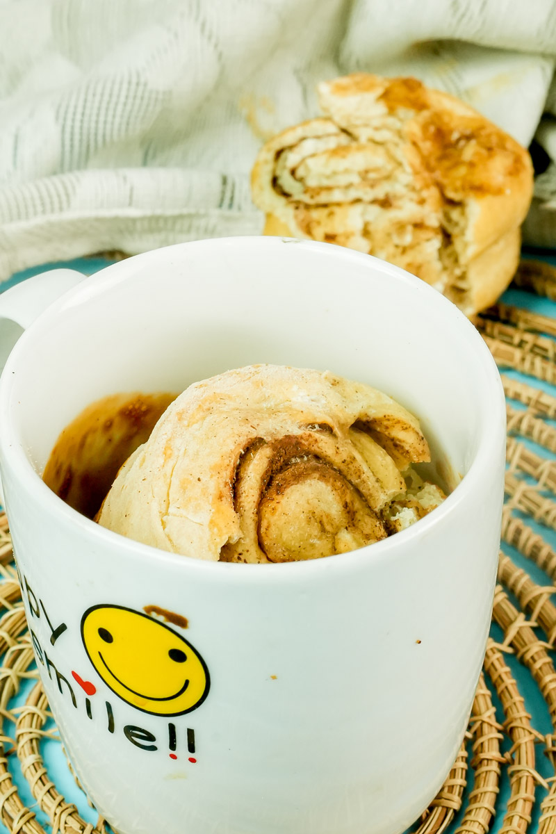 A warm cinnamon roll in a mug with a smiley face design