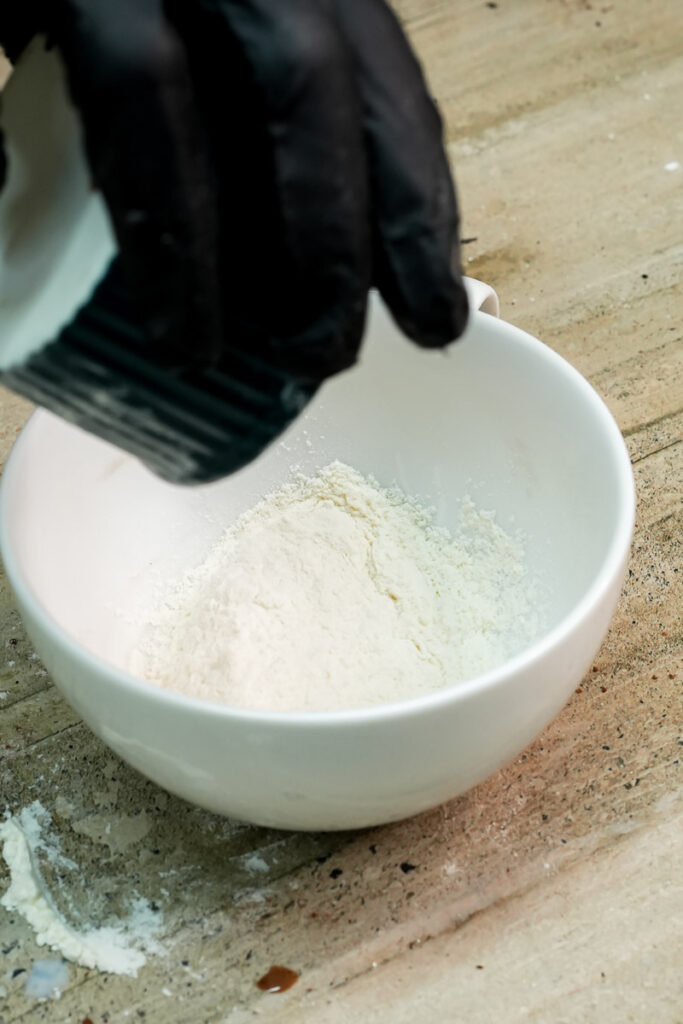 Adding all-purpose flour into a white ceramic mug