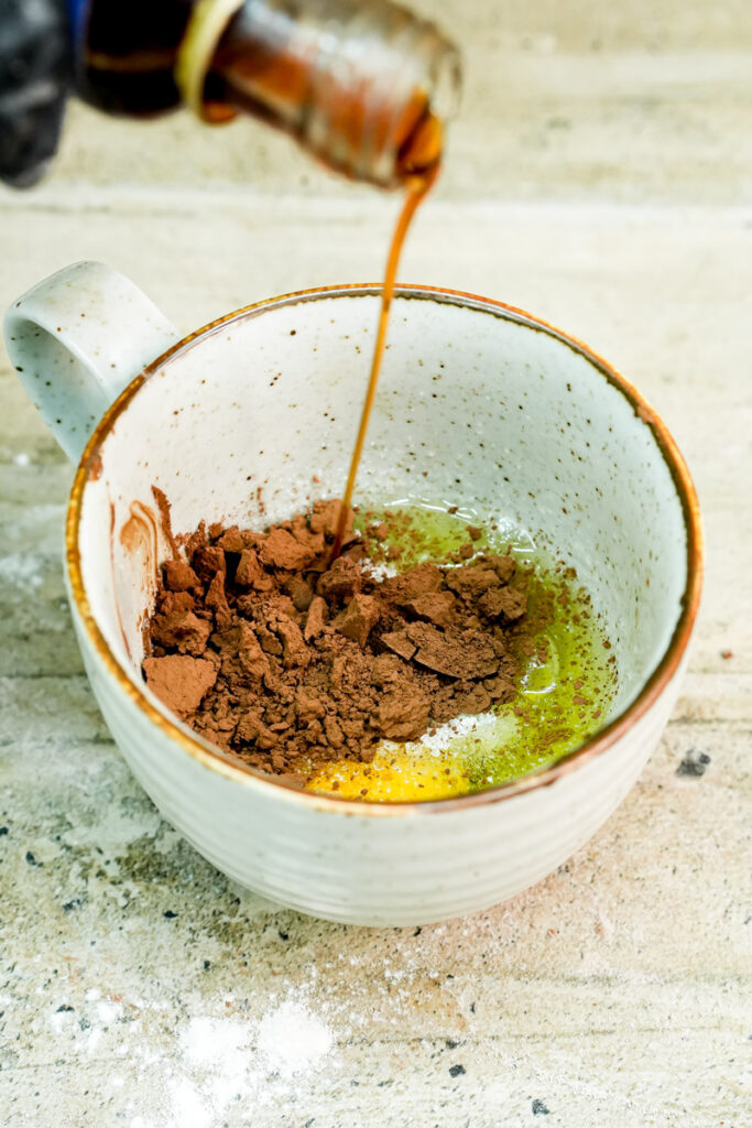 Adding cocoa powder and vanilla extract to the mug cake ingredients