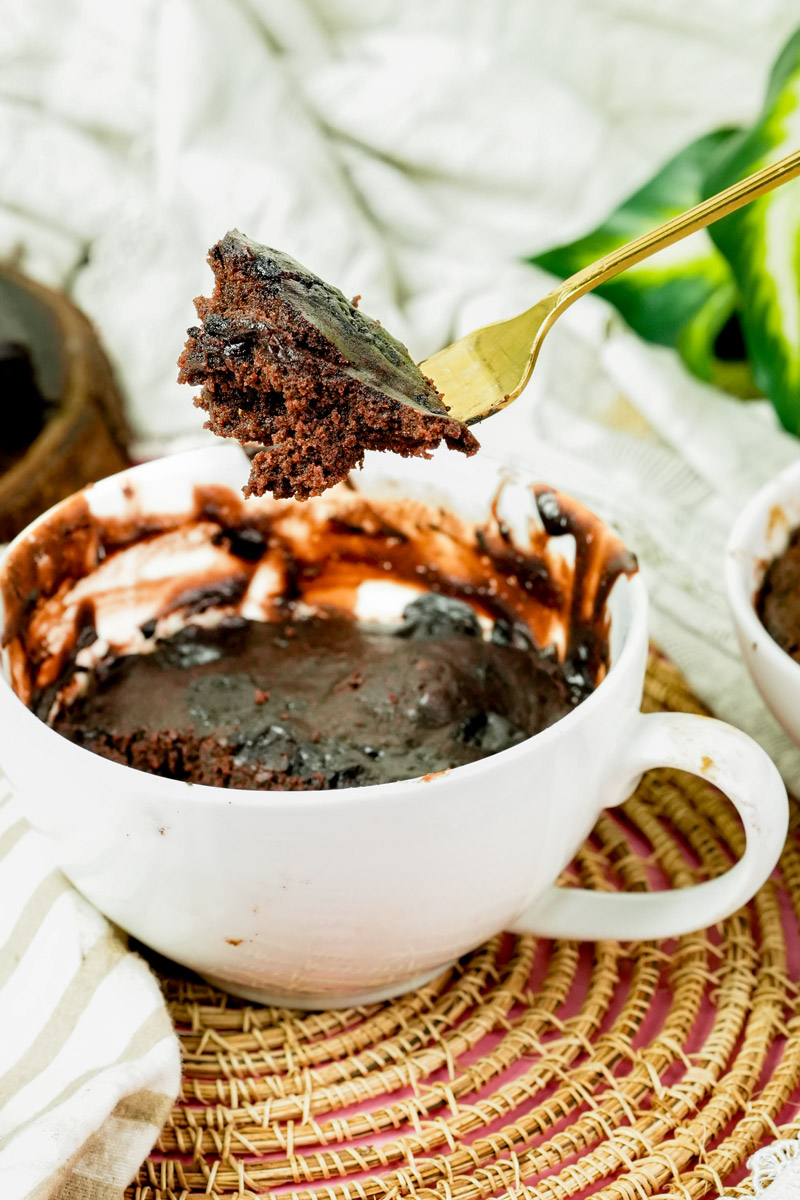 Bite-sized piece of chocolate mug cake held over the mug