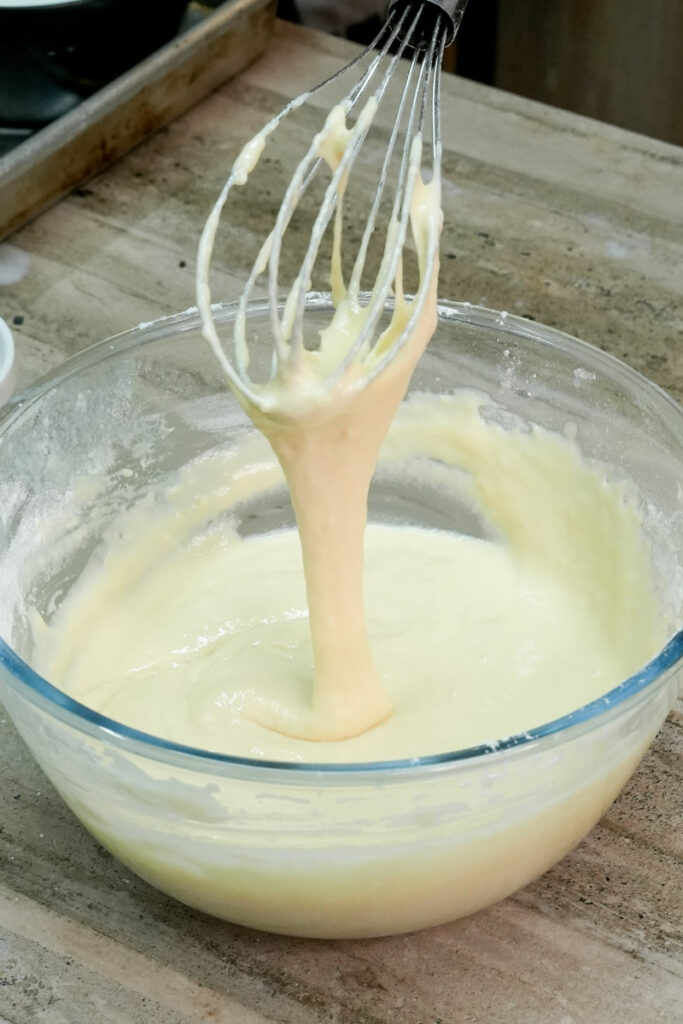Checking the smooth consistency of the pancake batter with a whisk