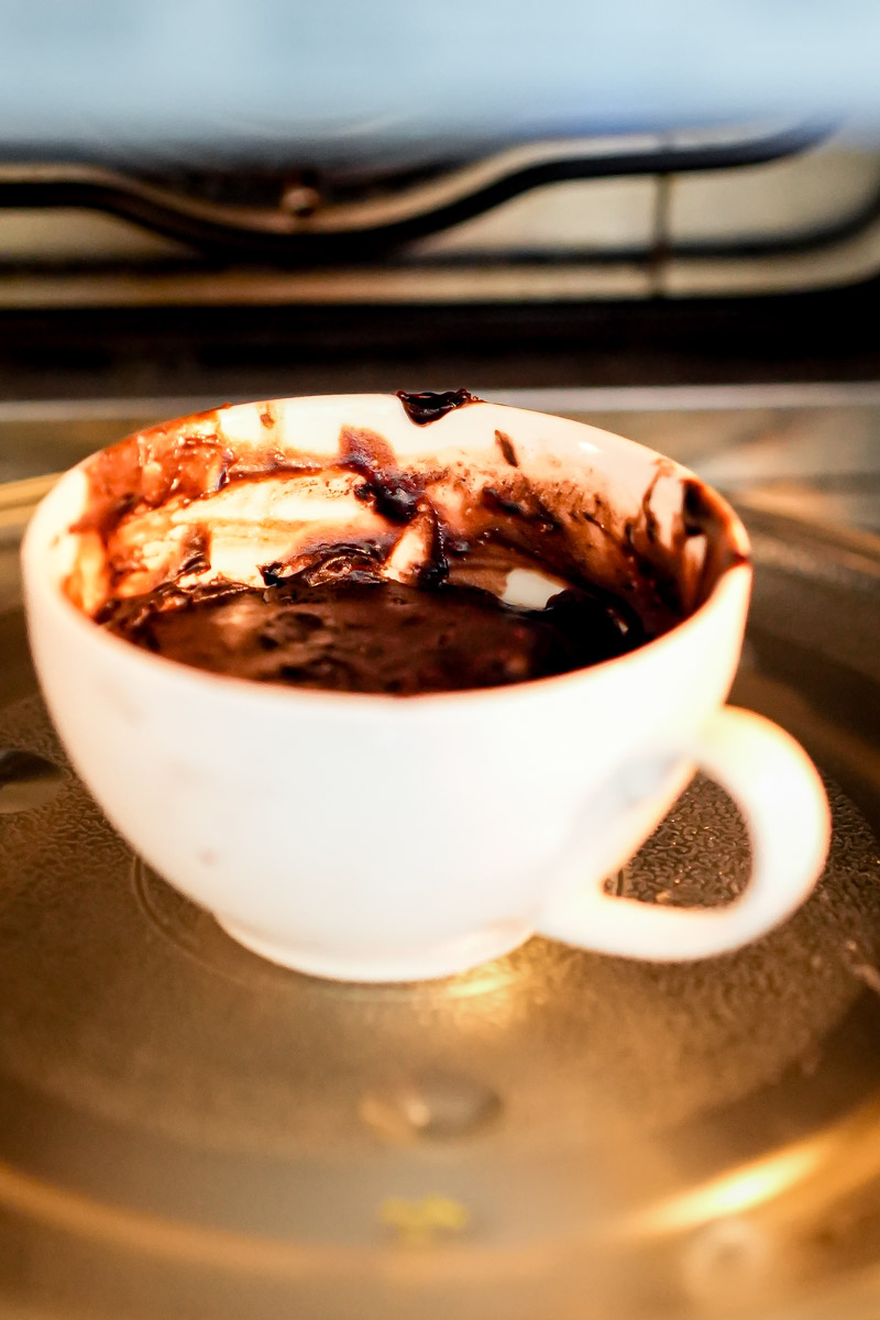 Chocolate mug cake baking inside a microwave