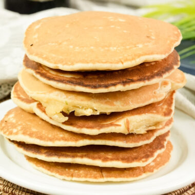 Close-up of a tall stack of fluffy golden brown American pancakes.