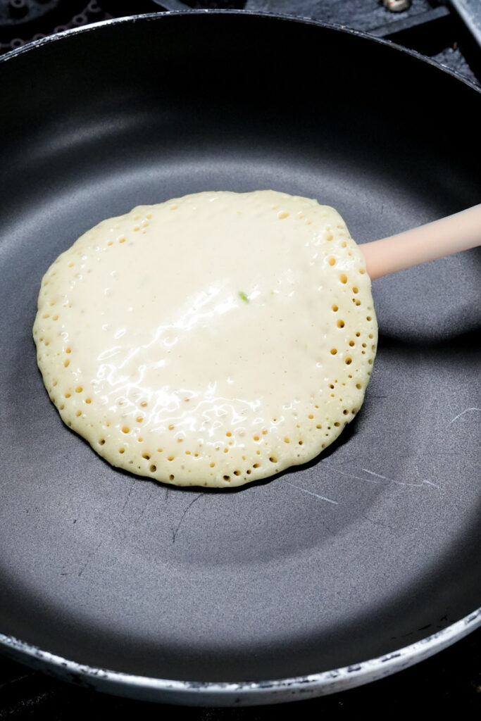 Cooking a lemon pancake in a pan until bubbles form on the surface