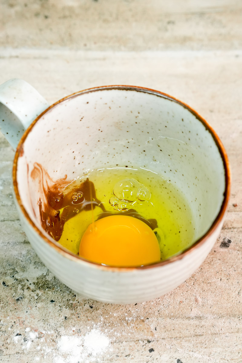 Cracking a fresh egg into the mug with Nutella