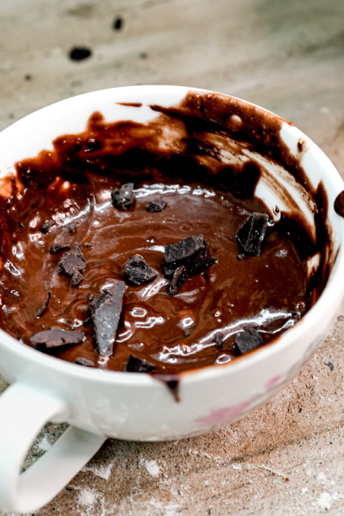 Eggless chocolate mug cake batter topped with dark chocolate chunks