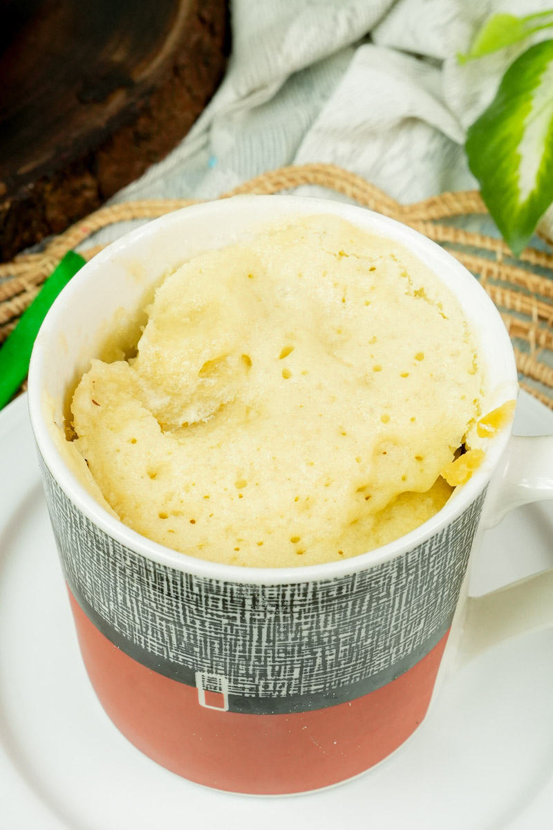 Freshly baked, fluffy vanilla mug cake in a red and grey mug