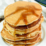Homemade American pancakes with syrup on a white ceramic dish.