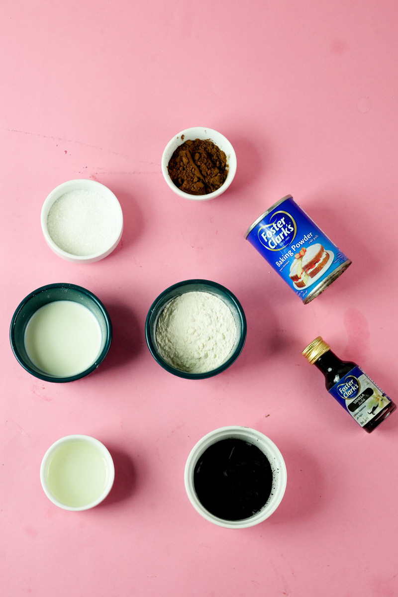 Ingredients for chocolate mug cake including flour, cocoa powder, milk, and vanilla
