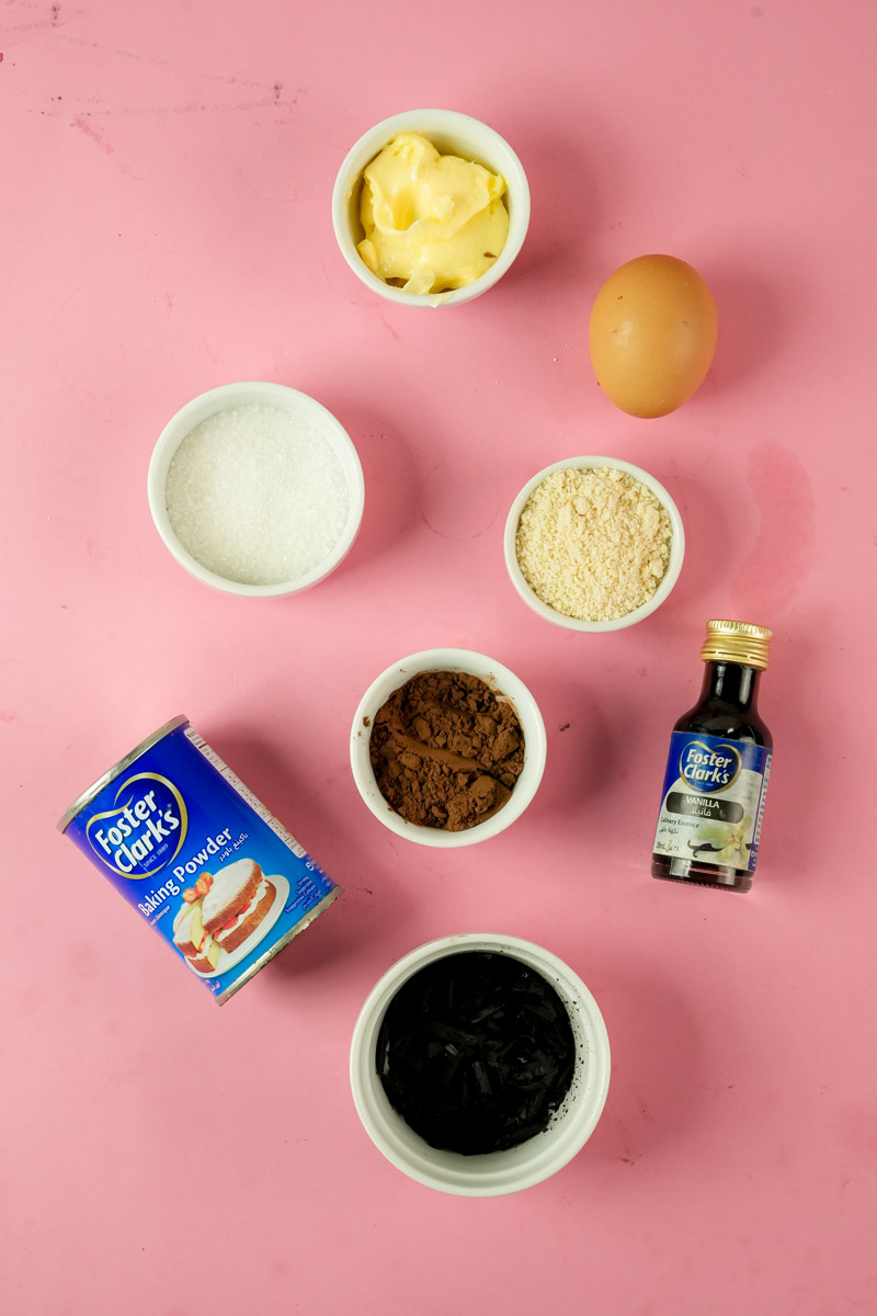 Keto chocolate mug cake ingredients on a pink background