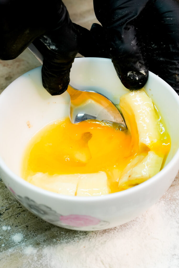 Mashing banana and egg together in a mug with a spoon