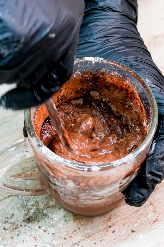 Mixing chocolate mug cake batter with a spoon in a glass mug