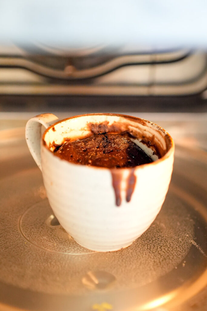 Nutella mug cake rising inside a microwave while cooking