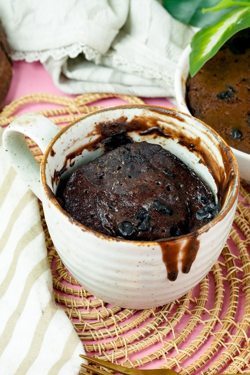 Finished Nutella mug cake served on a pink surface with a gold fork