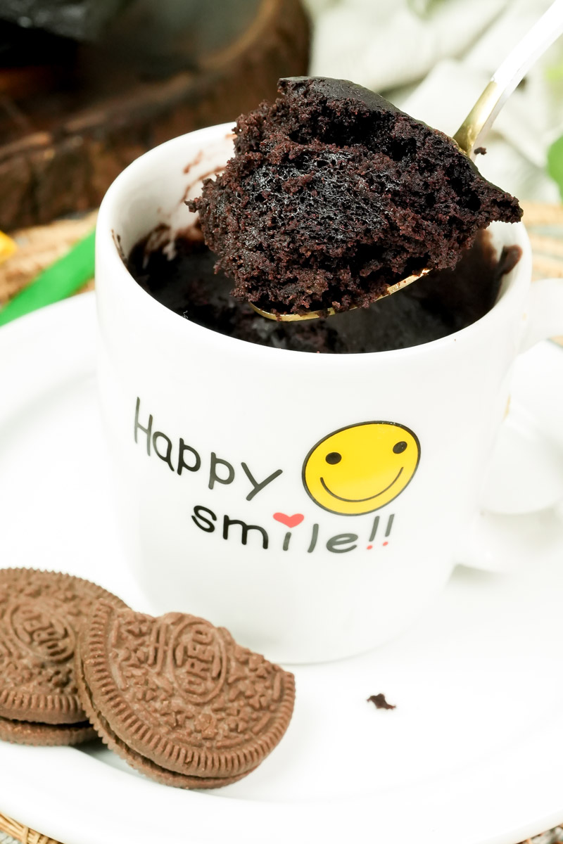 Decadent Oreo mug cake bite with chocolate cookies in the background