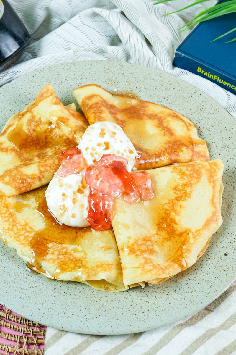 Pancakes soaked in maple syrup with fruit jam and cream