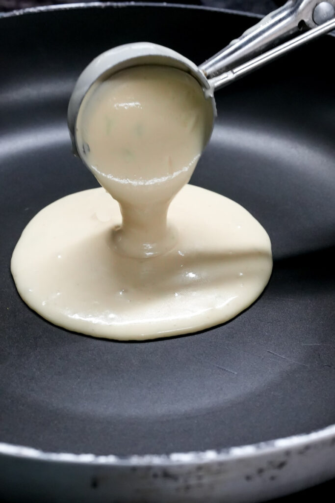 Scooping lemon pancake batter into a preheated non-stick frying pan