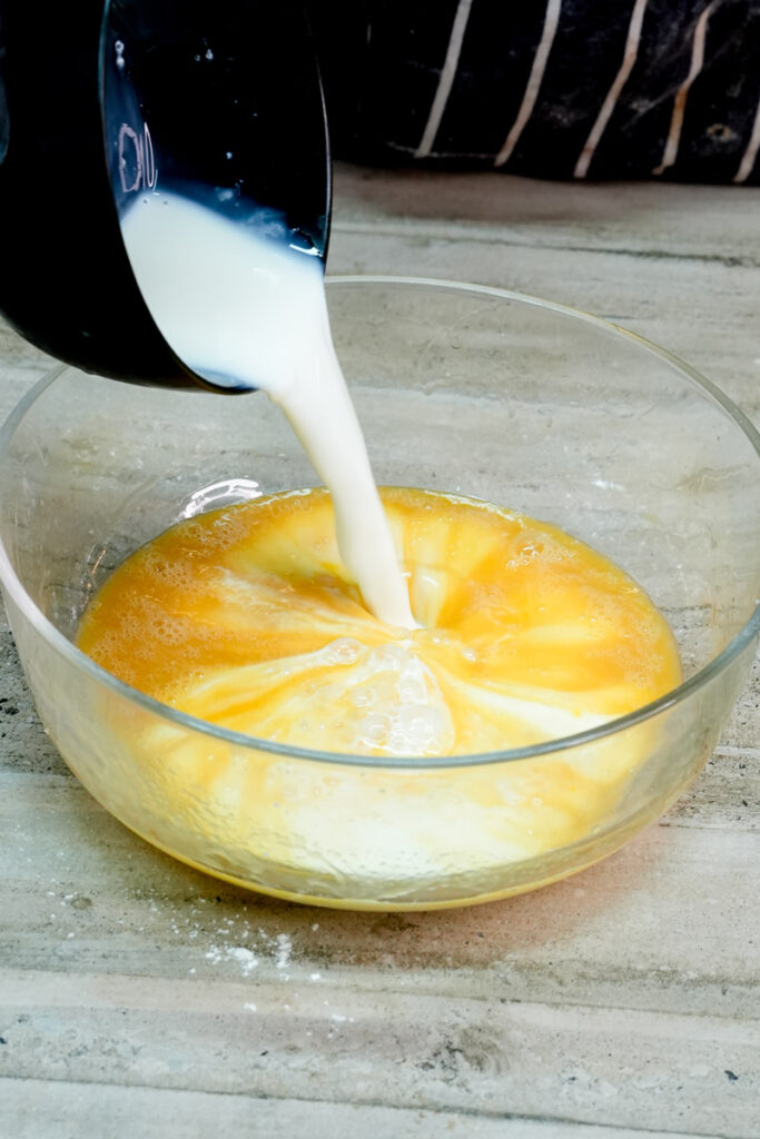 Pouring fresh milk into the bowl to make lemon pancake batter