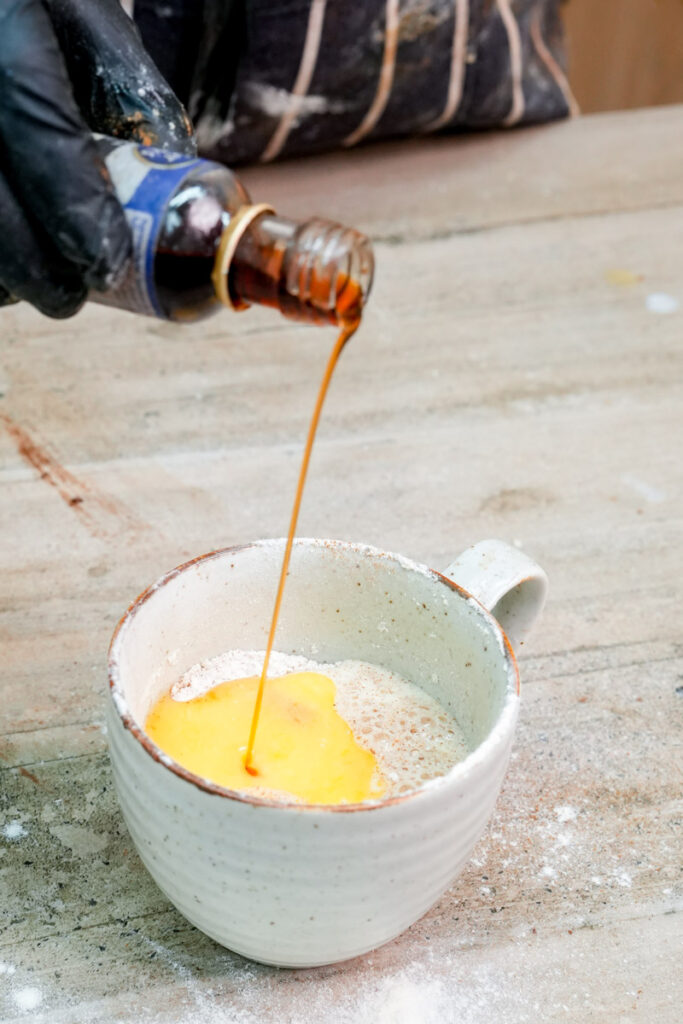 Pouring vanilla extract into the mug cake mixture