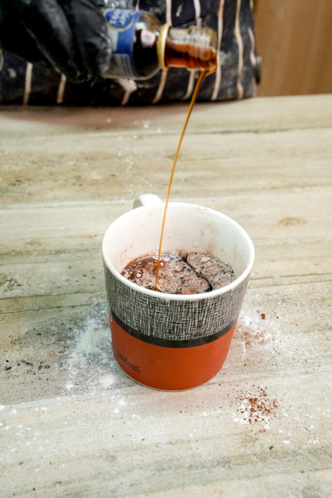 Pouring vanilla extract into the vegan cake batter