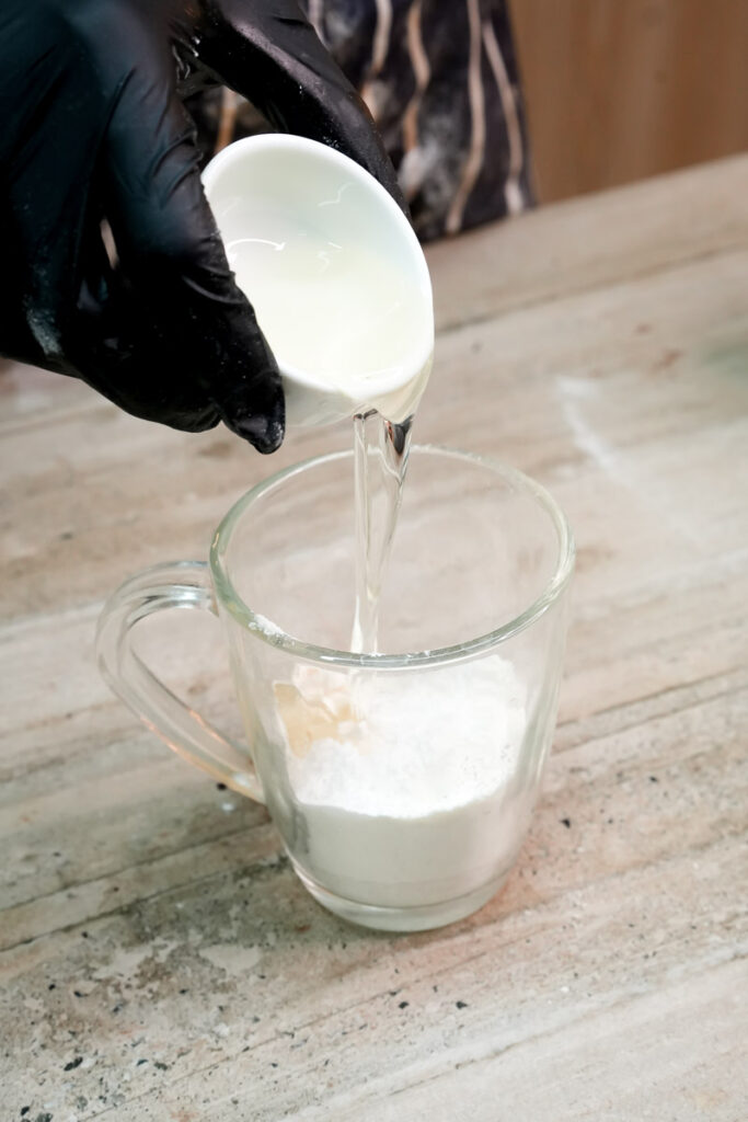 Pouring vegetable oil into a glass mug with dry cake ingredients