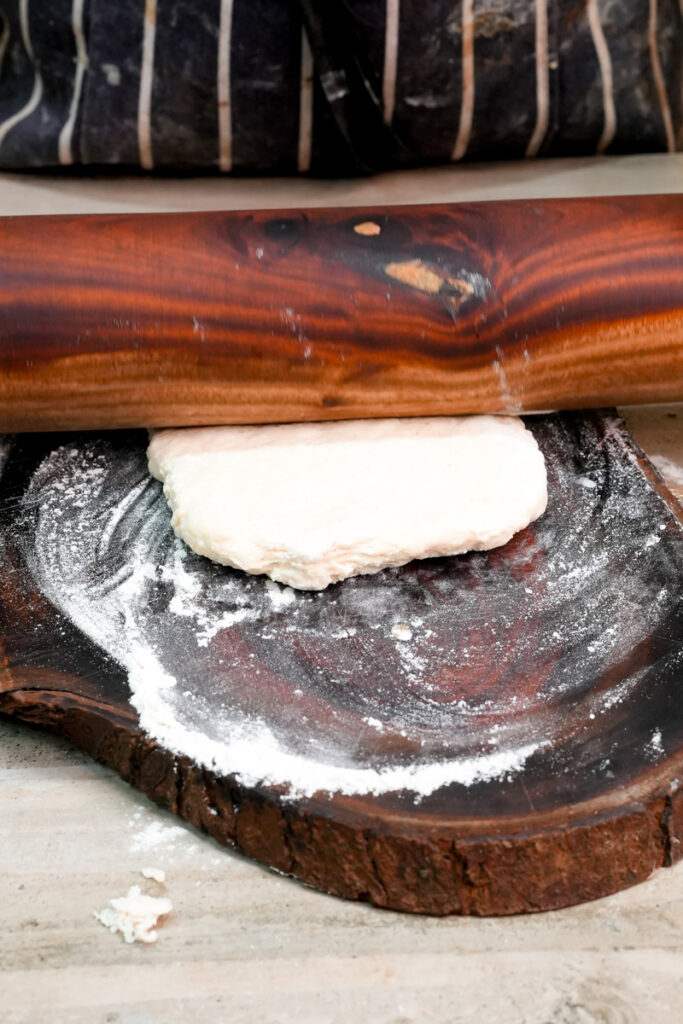Rolling out a small piece of dough on a wooden board with a rolling pin