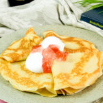 Full table setting of Russian pancakes with syrup and cream garnishes