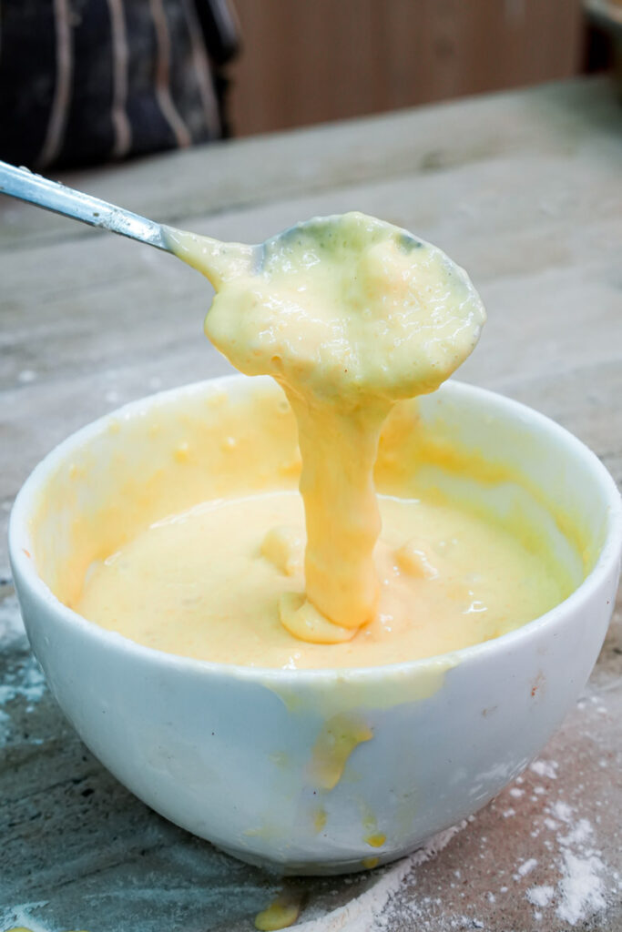 Smooth banana mug cake batter dripping from a spoon into the mug