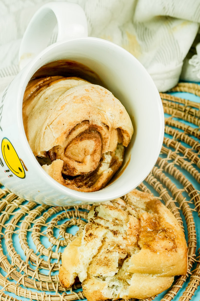 Soft and gooey cinnamon roll in a mug served on a woven mat