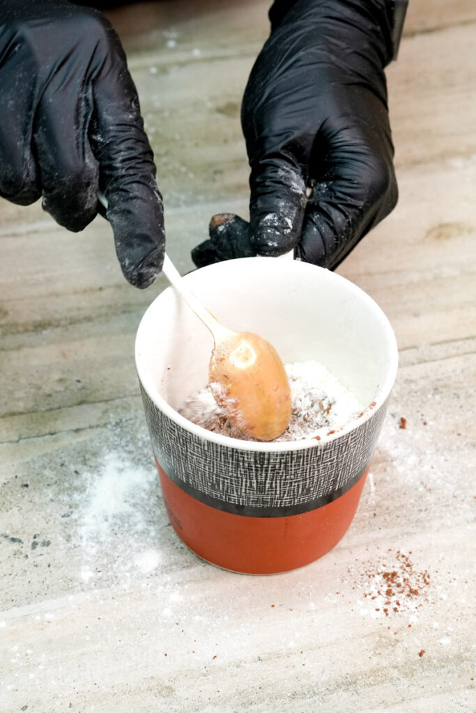 Stirring flour and cocoa powder in a mug with a spoon