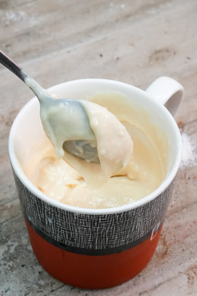 Stirring vanilla mug cake batter with a spoon until smooth