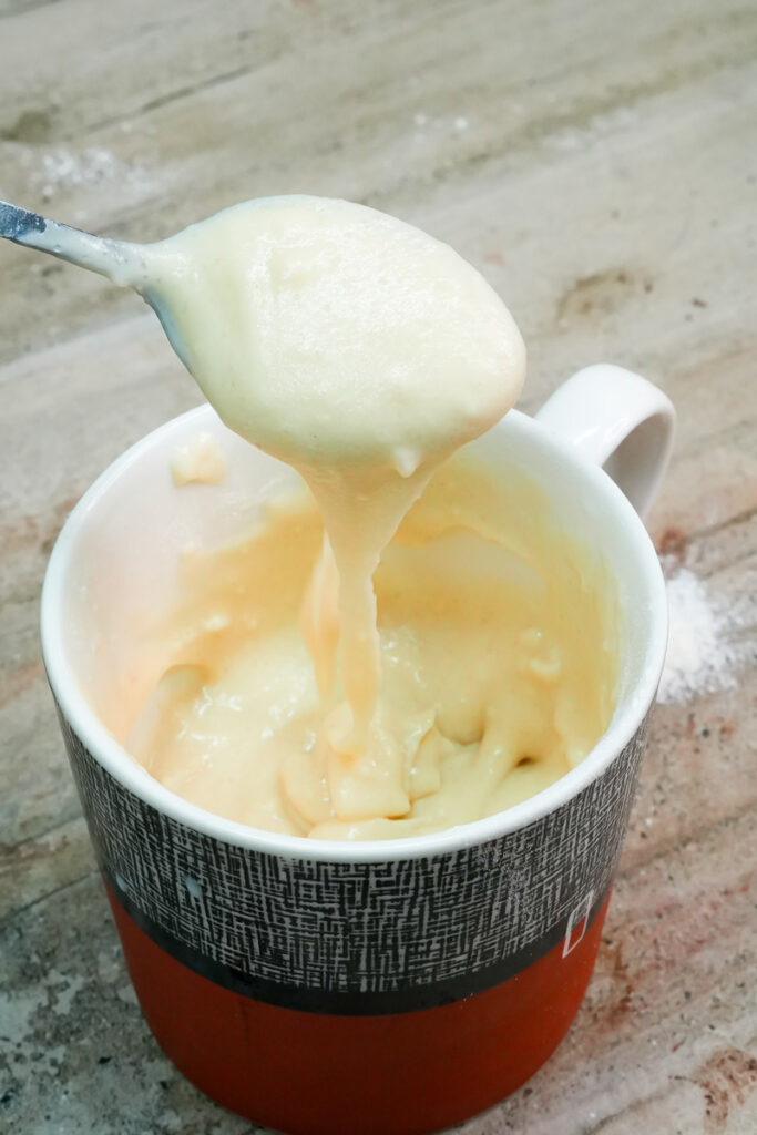 Thick and creamy vanilla mug cake batter on a spoon
