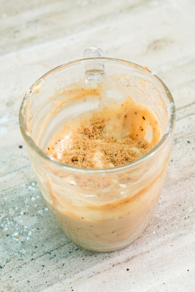 Topping the coffee mug cake batter with a sprinkle of brown sugar
