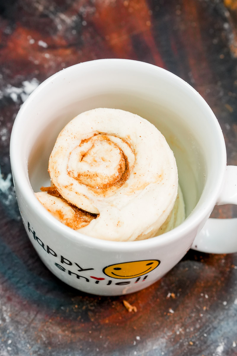 Unbaked cinnamon roll dough placed inside a white mug