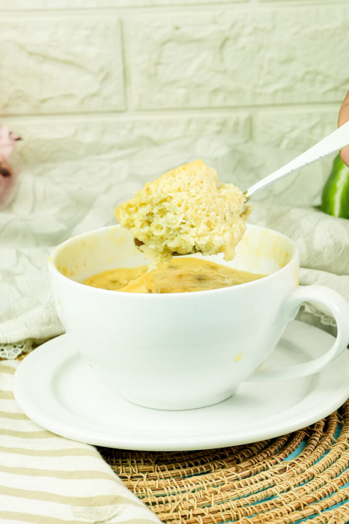 Lifting a bite of warm banana mug cake with a silver spoon