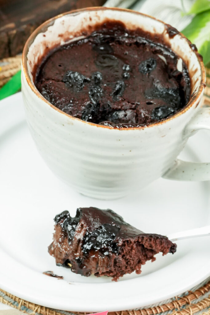 Finished brownie in a mug with a spoonful served on a white plate