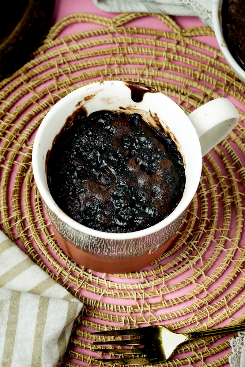 Top view of a moist, dark chocolate microwave mug cake in a red and grey cup